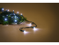 Бели LED коледни лампички върху зелен боров клон, на топъл кафяв фон.