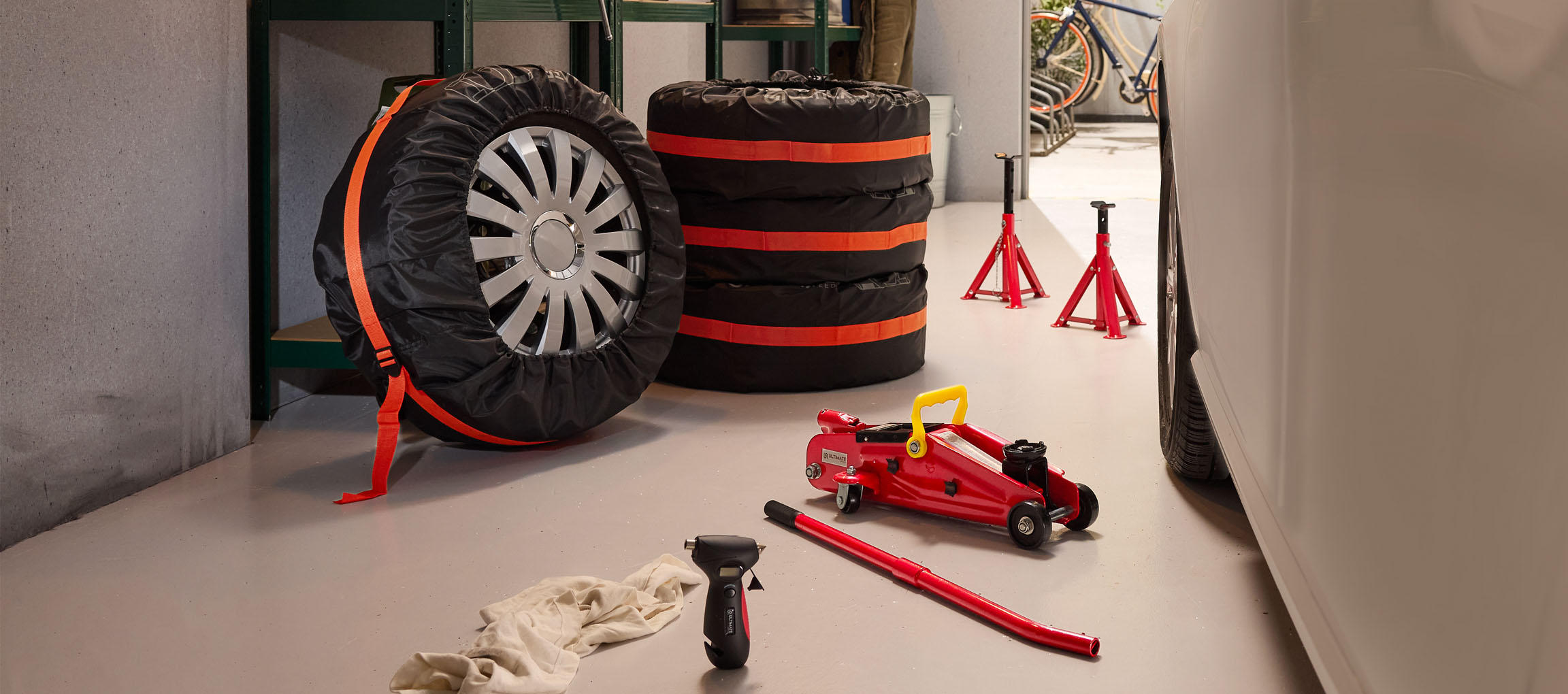 Автомобилни гуми с калъфи, крик и стойки в гараж.