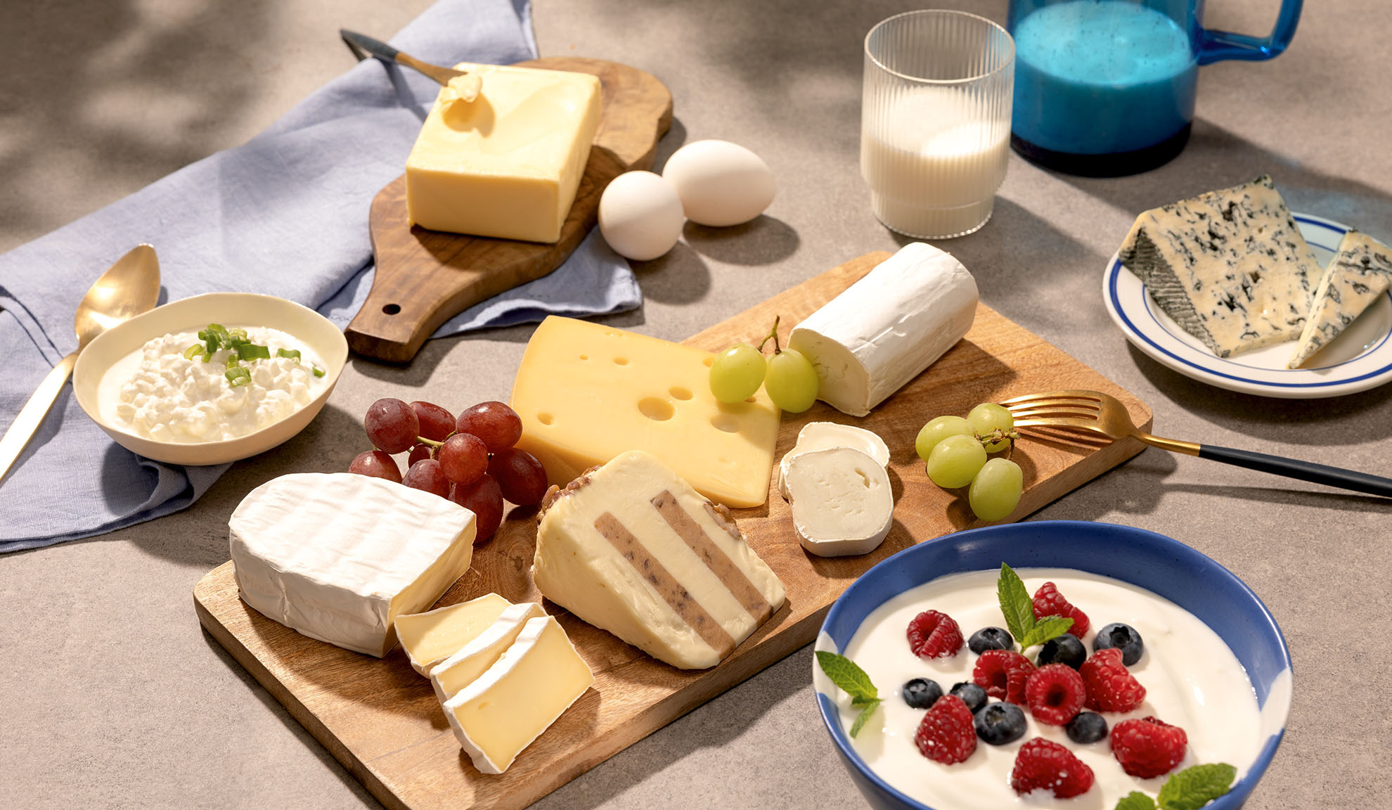 Разнообразие от сирена, грозде и млечни продукти като извара, мляко и кисело мляко с горски плодове.