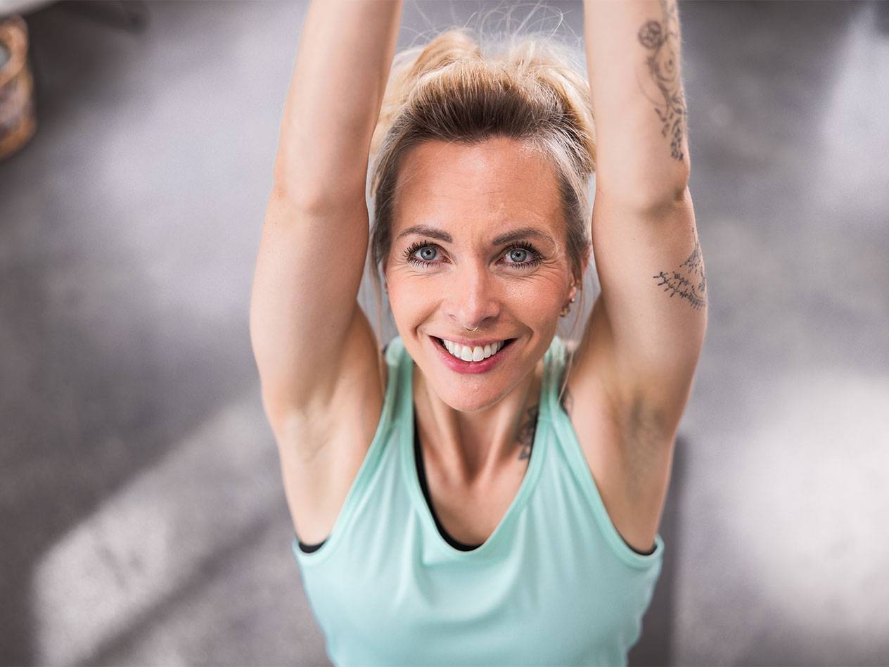 Руса жена в светлосиня потник се усмихва към камерата.