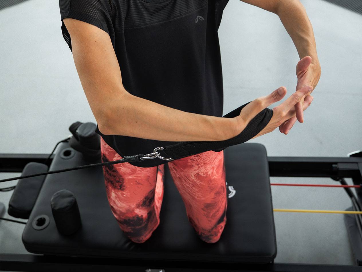 Жена тренира с ластици за съпротивление на пилатес машина.