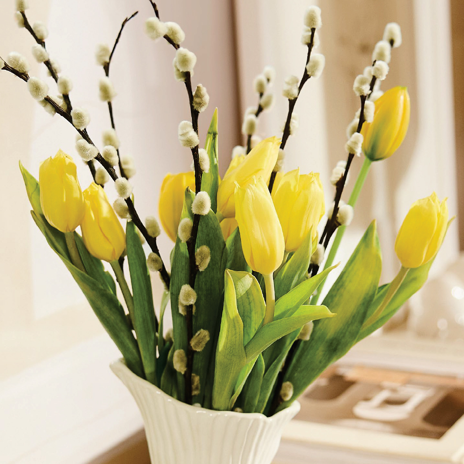Букет от жълти лалета и върбови клонки в бяла ваза.