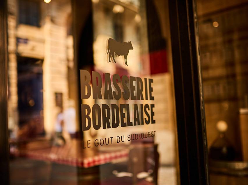 Табела на Brasserie Bordelaise със силует на крава и текст „Le Goût du Sud-Ouest“.