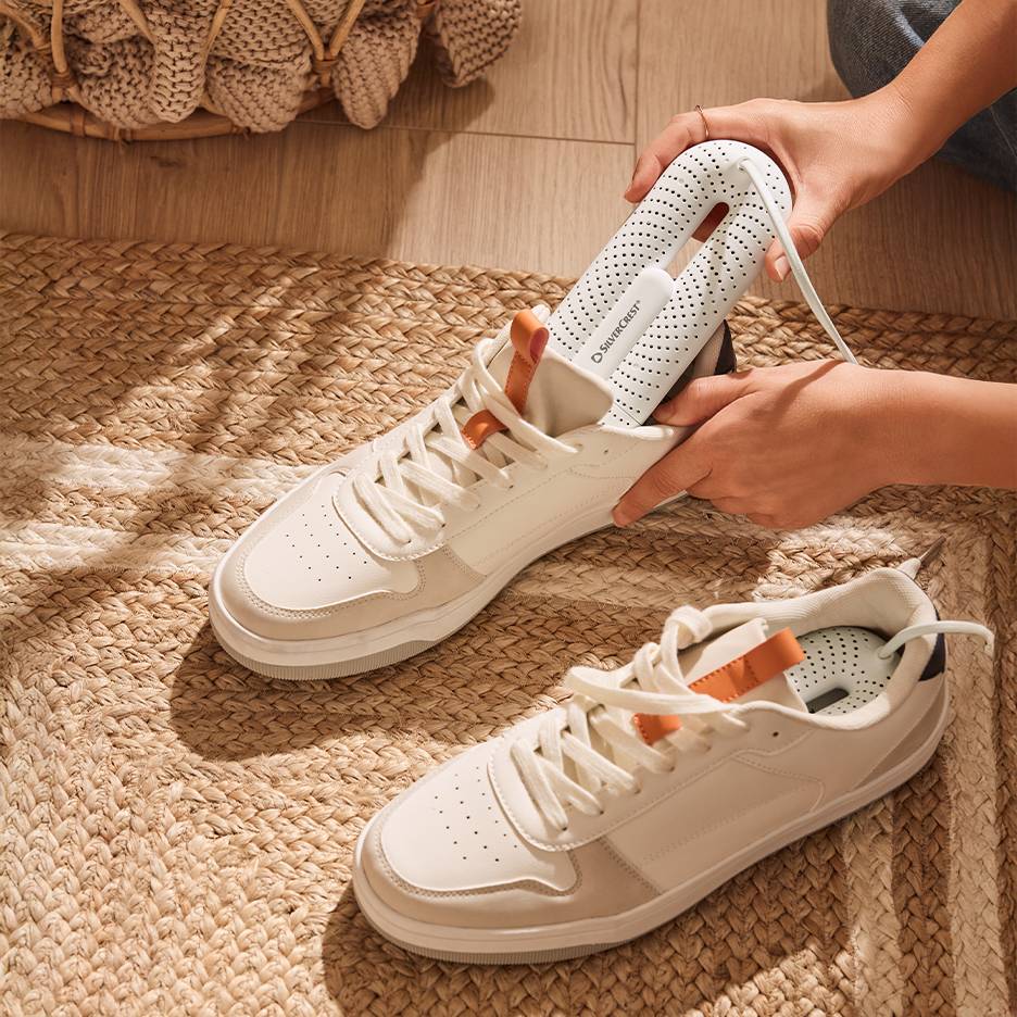 Сушилня за обувки Silvercrest в бели маратонки върху плетена постелка.