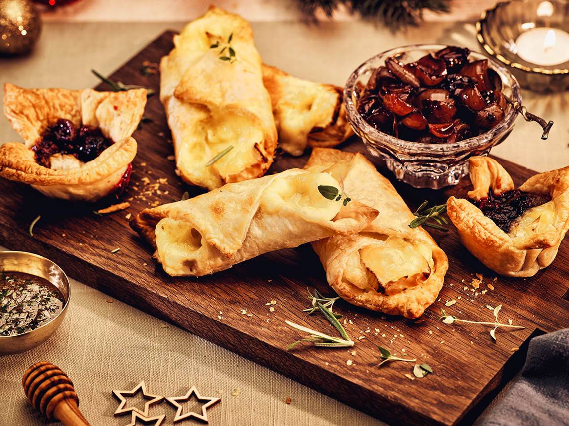 Тарти с бри и конфитюр, поднесени на дървена дъска.