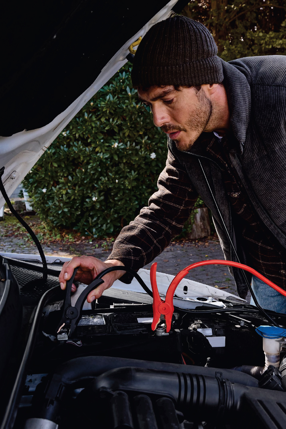 Мъж свързва кабели за подаване на ток към акумулатор на кола.