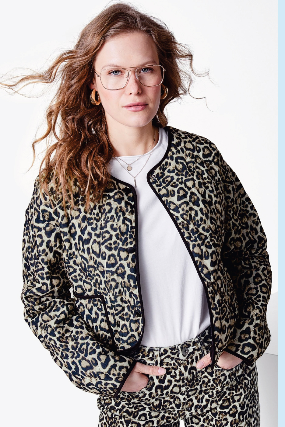 Жена с леопардово яке и панталон, бяла тениска и очила.