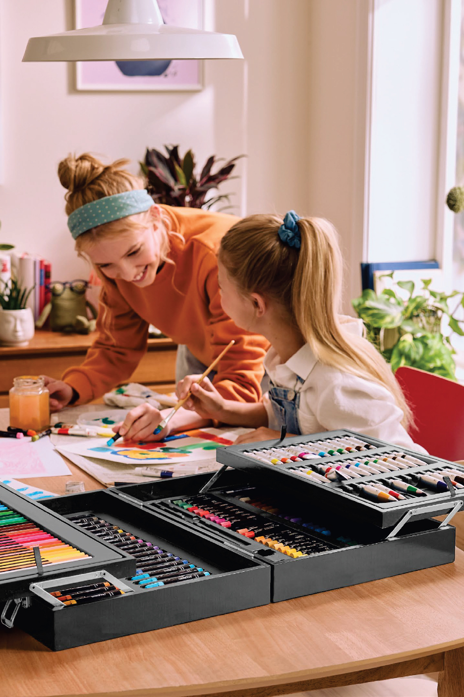 Две момичета рисуват с голям комплект за рисуване от Lidl, пълен с маркери и пастели.