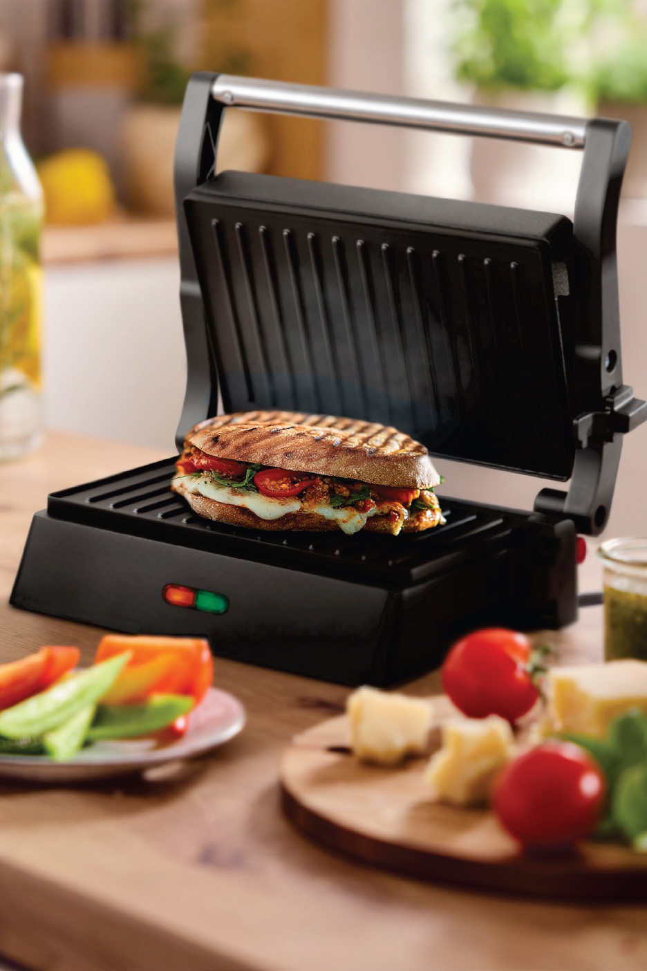 Панини грил с отворен капак и приготвен сандвич, заобиколен от пресни съставки.