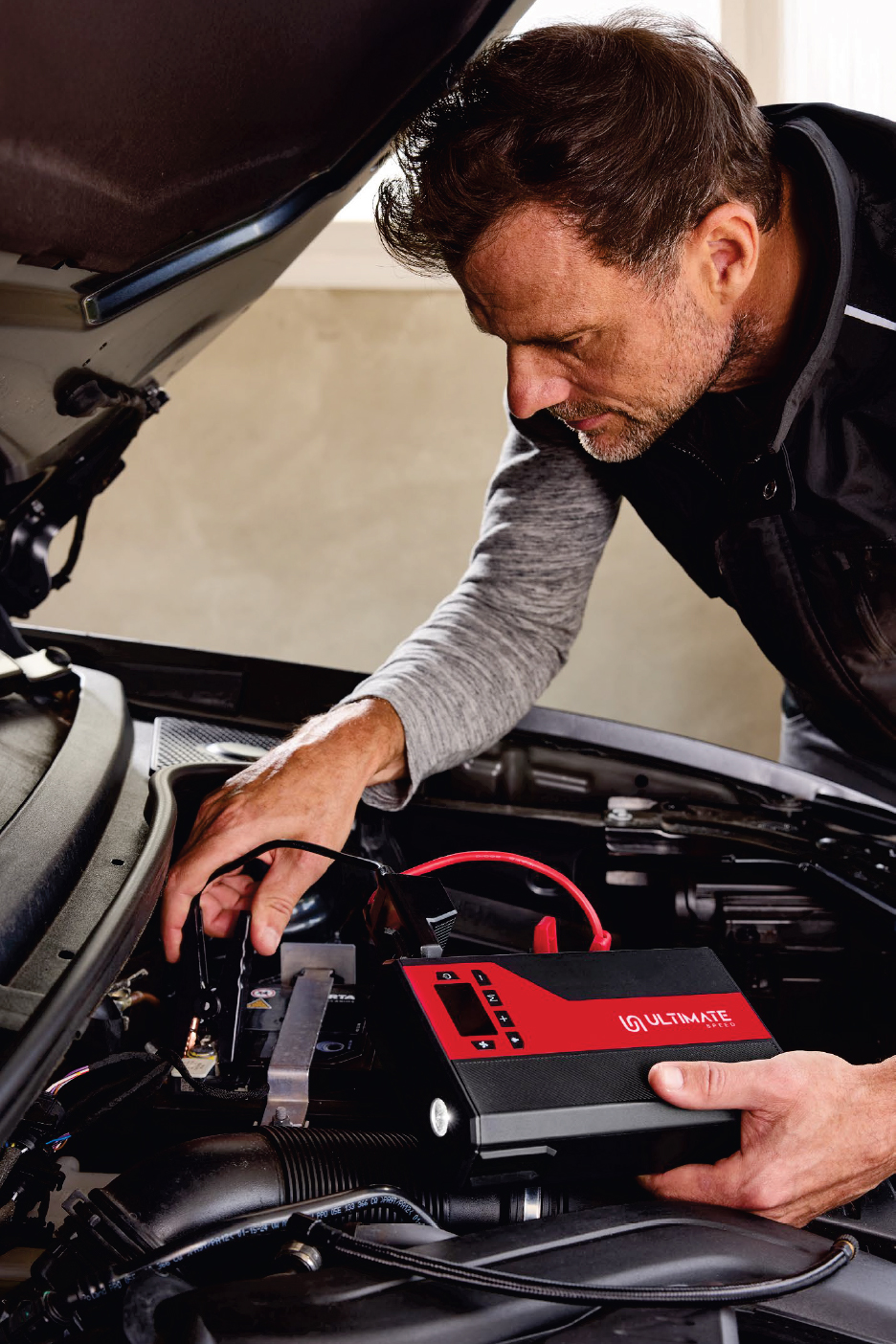 Черно-червен стартов пакет Ultimate, свързан към акумулатор на кола.