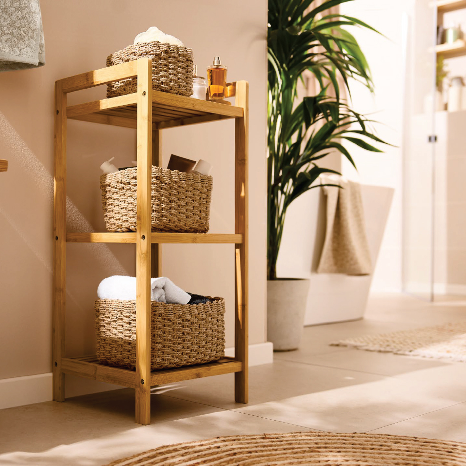 Дървена етажерка за баня с плетени кошници, пълни с кърпи и тоалетни принадлежности.