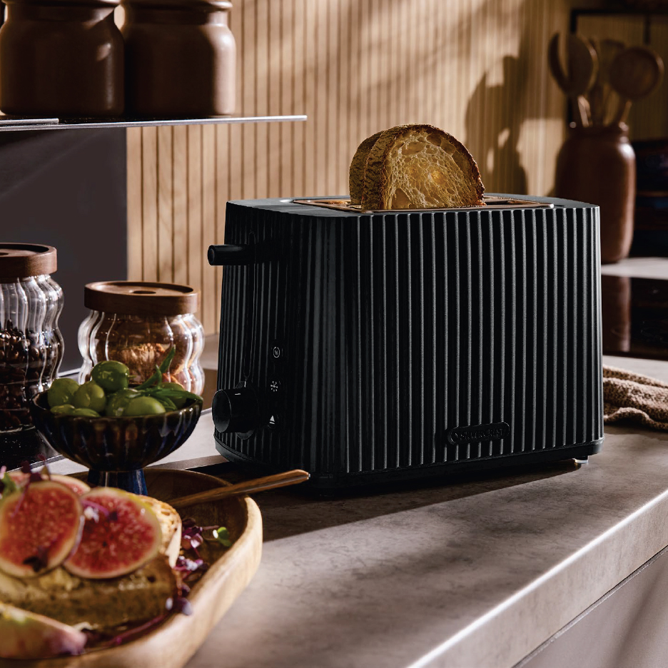 Черен тостер с филия хляб, бурканчета с подправки и купа маслини на кухненски плот.