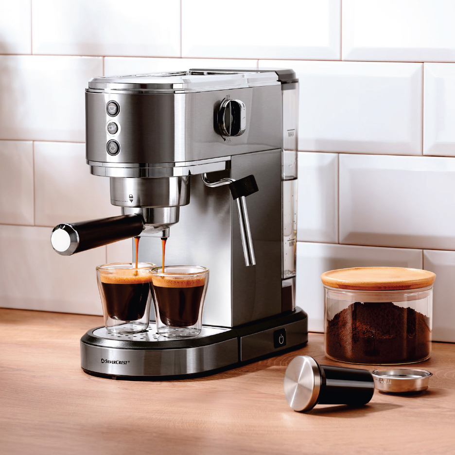 Еспресо машина, наливаща кафе в две чаши, до нея буркан със смляно кафе.