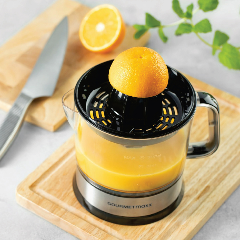 Цитрусова сокоизстисквачка с портокал, пълен с портокалов сок, върху дървена дъска.