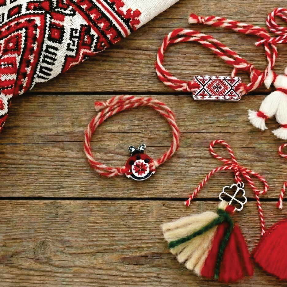 Мартеници, гривни и декорации в червено и бяло върху дървена повърхност.