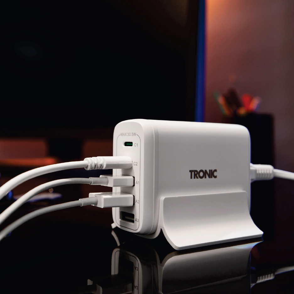 Бял Tronic USB хъб за зареждане с множество кабели, включени в тъмна стая.