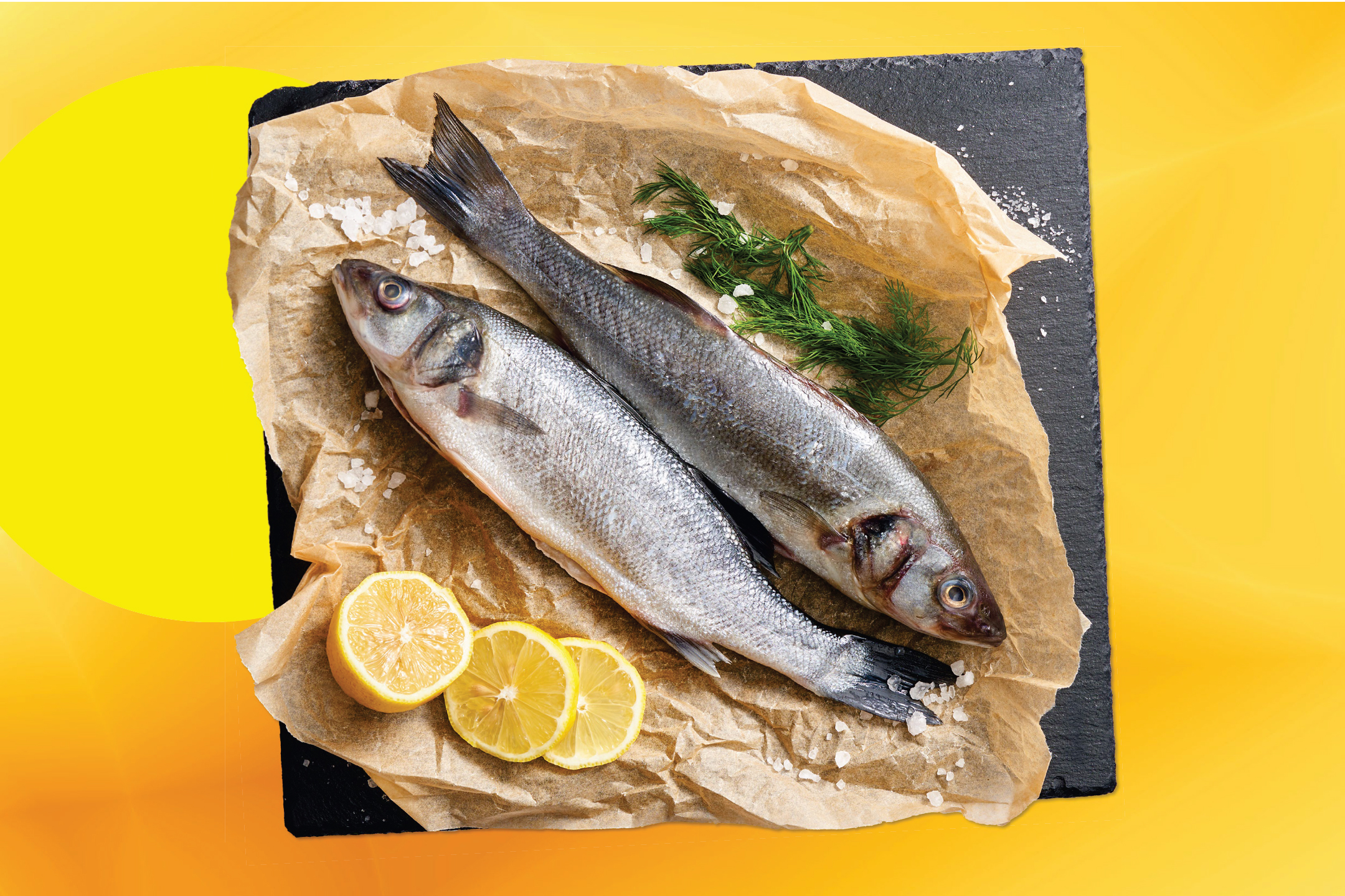 Две пресни риби върху хартия за печене с лимон, копър и морска сол.