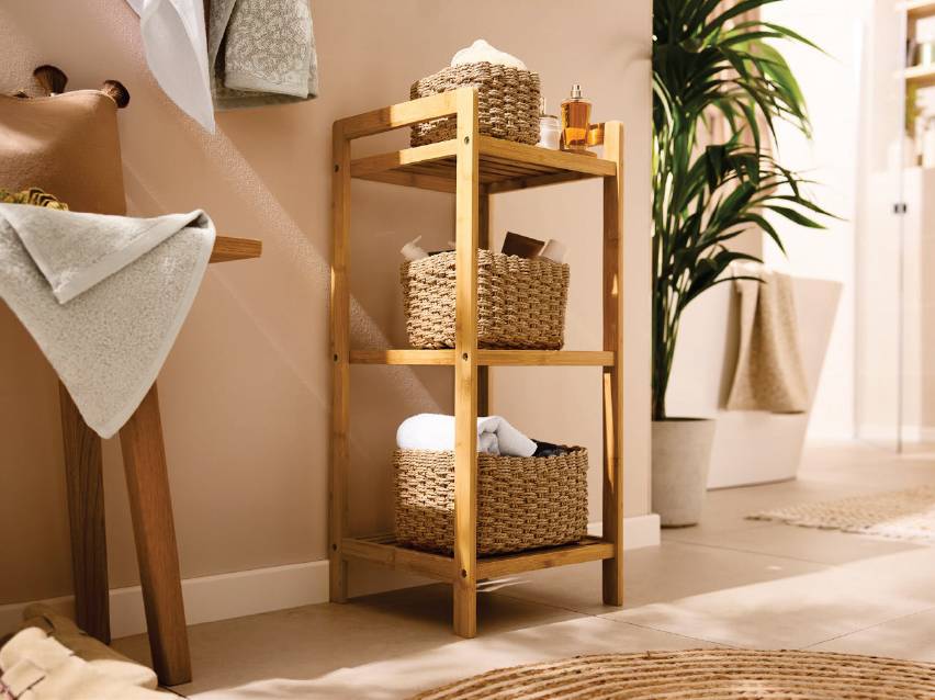 Дървена етажерка за баня с три рафта, пълни с плетени кошници и кърпи.