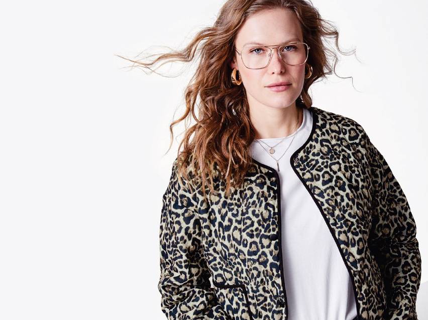 Жена с леопардово яке, бяла тениска, златни обеци и очила