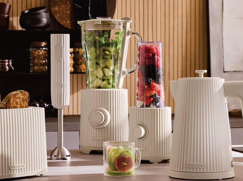 Кухненски уреди в кремав цвят: пасатор, блендер с плодове и кана за вода, на плот.