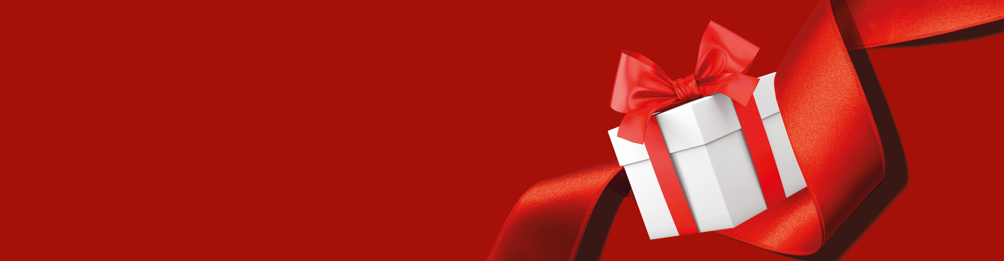 Бяла подаръчна кутия с червена панделка на червен фон.