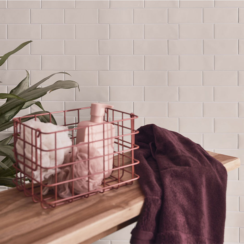 Декор за баня с бели плочки, дървена пейка, кошница със сапун и кърпи.