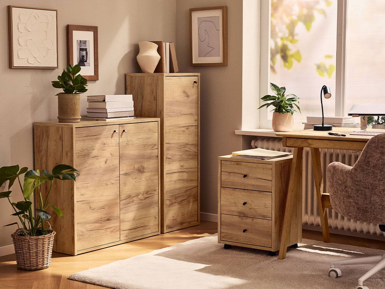 Домашен офис със светли дървени шкафове, офис стол и настолна лампа.