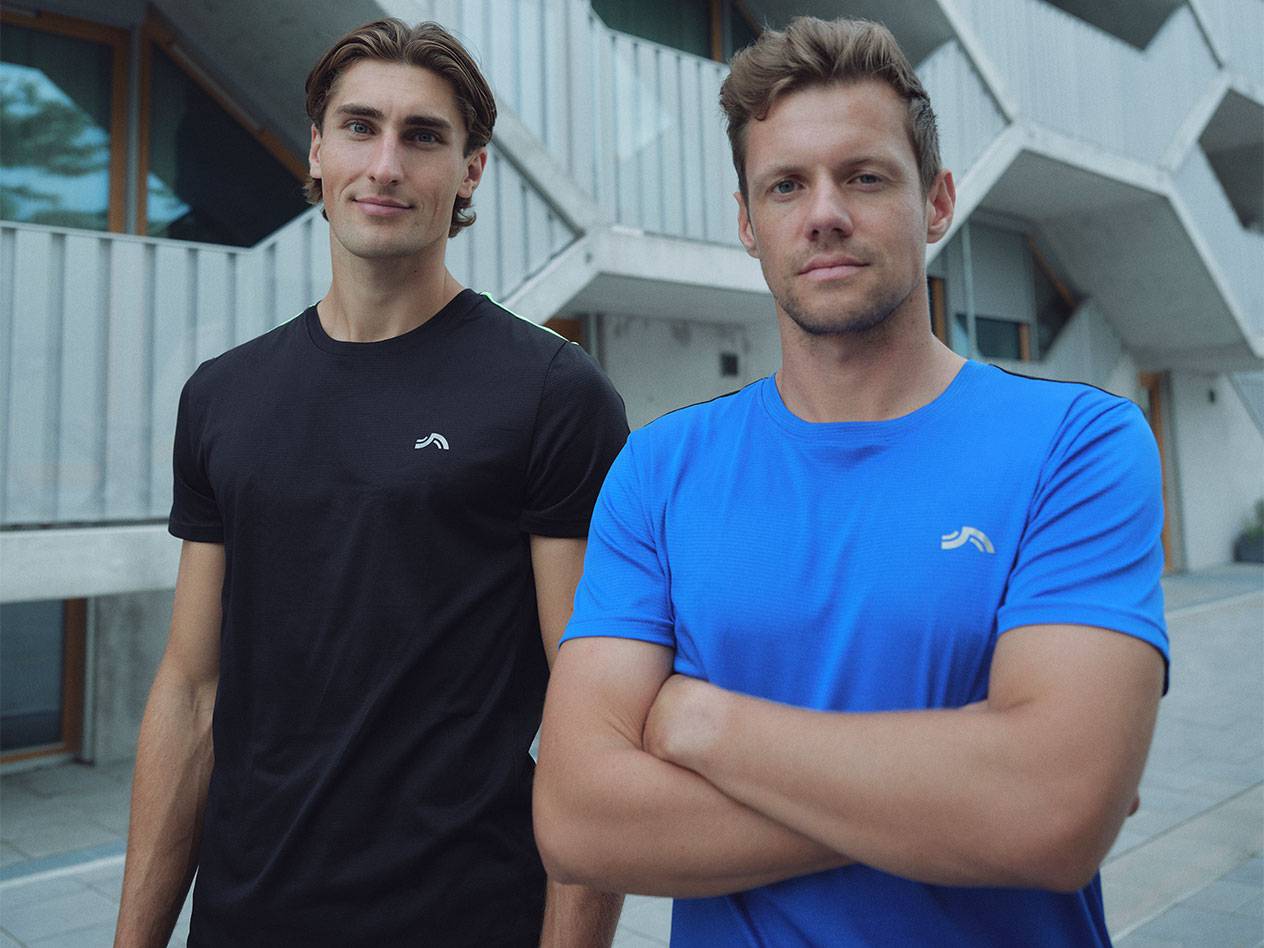 Двама мъже в черни и сини спортни тениски с лого.