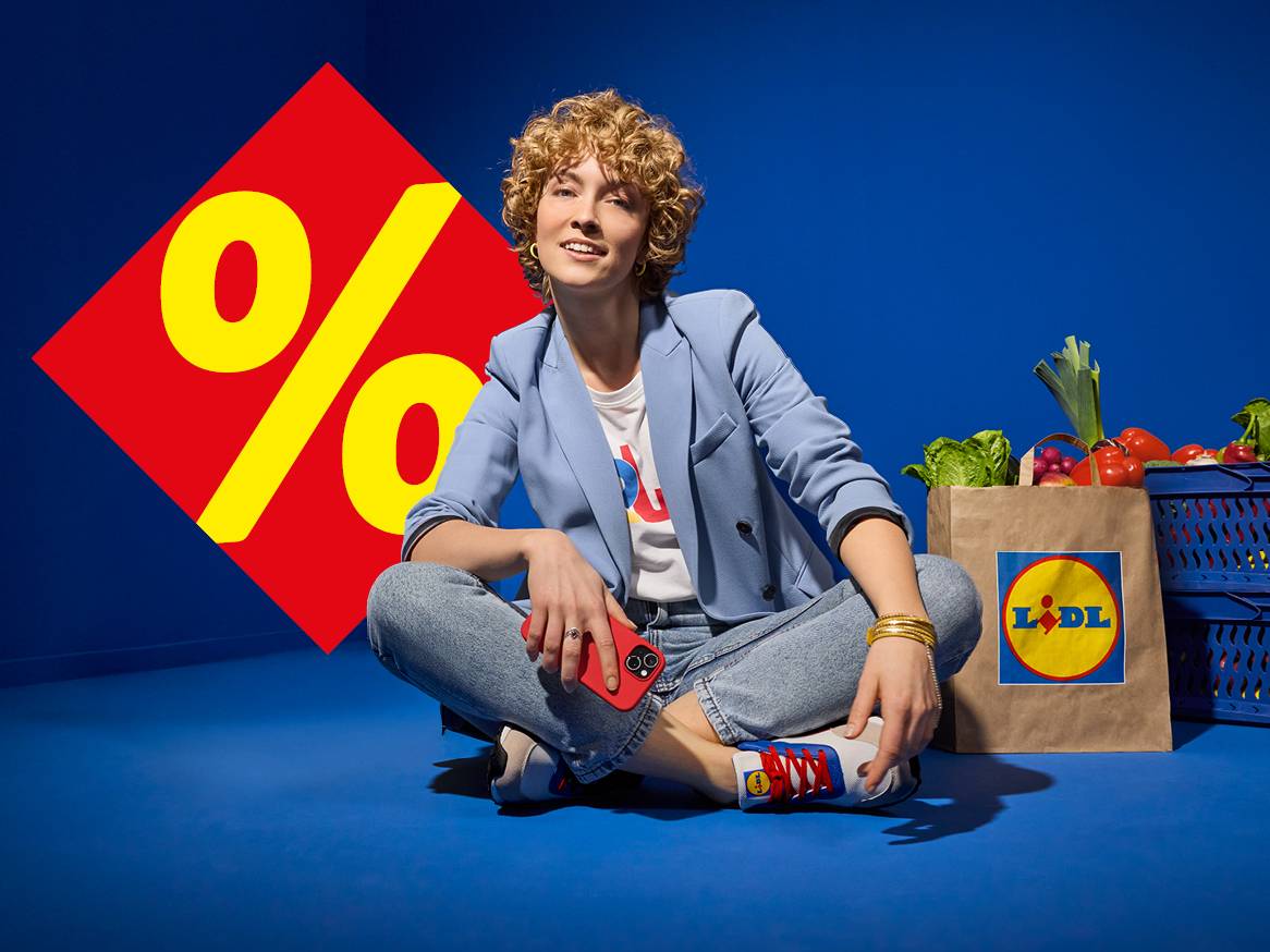 Жена седи до пазарска чанта на Lidl с пресни продукти и голям знак за процент.