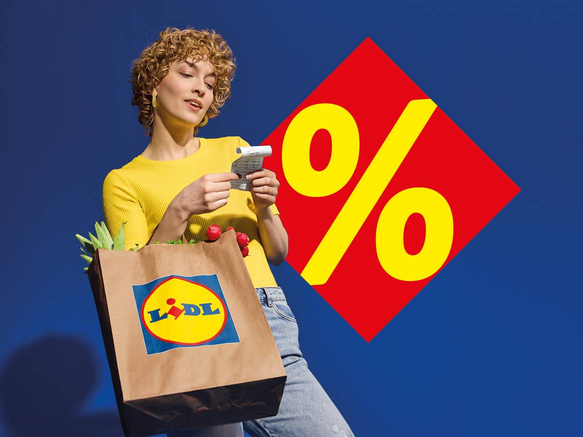 Жена с пазарска чанта, пълна със зеленчуци, проверява касова бележка, на фона на голям знак за процент.