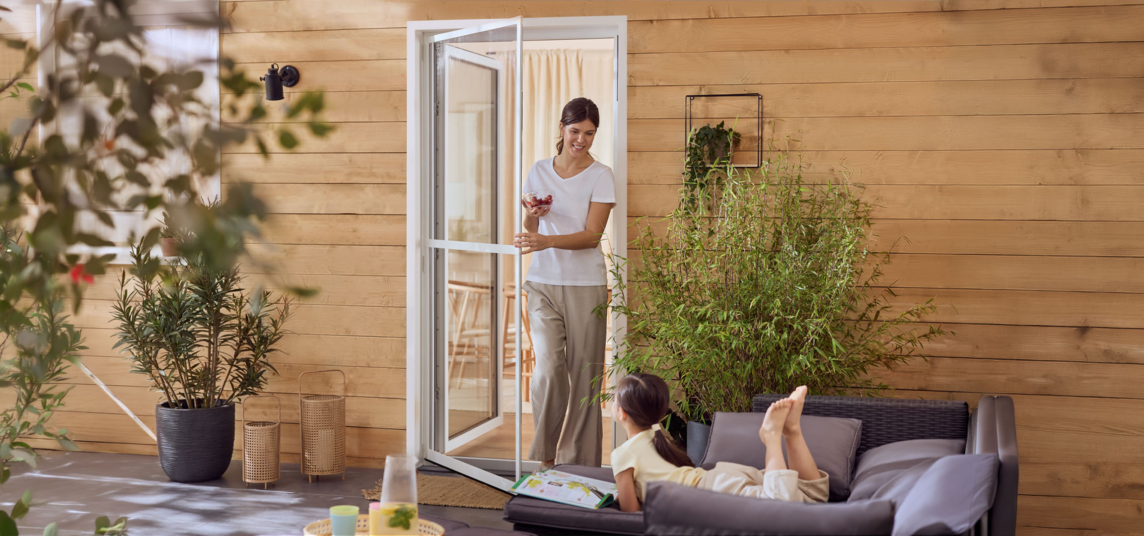 Жена и момиче се наслаждават на вътрешен двор с градински мебели и растения.