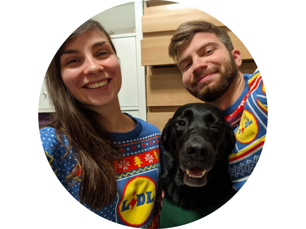 Двама души и куче носят коледни пуловери на Lidl, усмихнати към камерата.