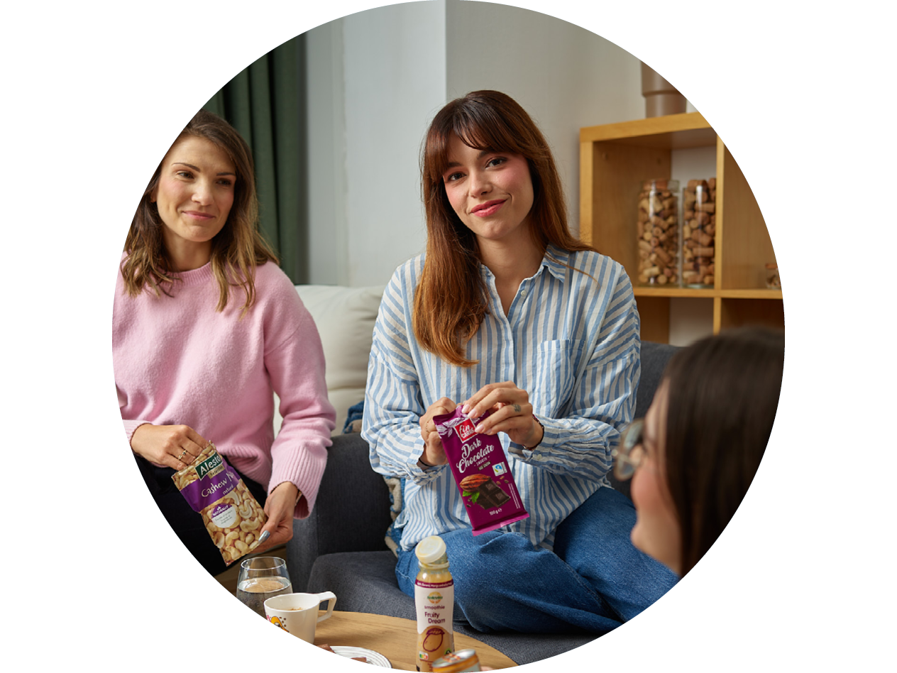 Две жени се наслаждават на кашу Alesto и черен шоколад с приятелка.
