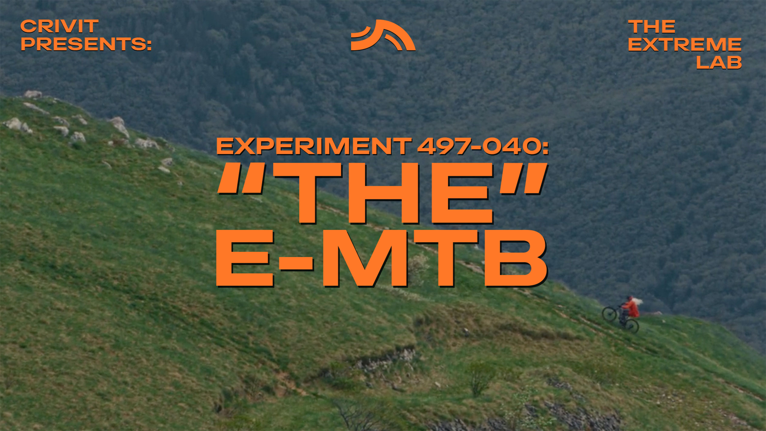 Планински колоездач на тревист склон, с текст 'THE E-MTB' и 'THE EXTREME LAB'.