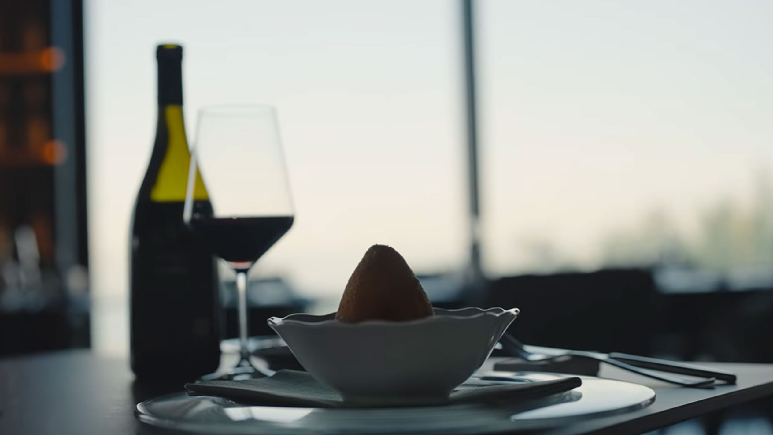 Бутилка червено вино и чаша до едно аранчино в купа на маса.