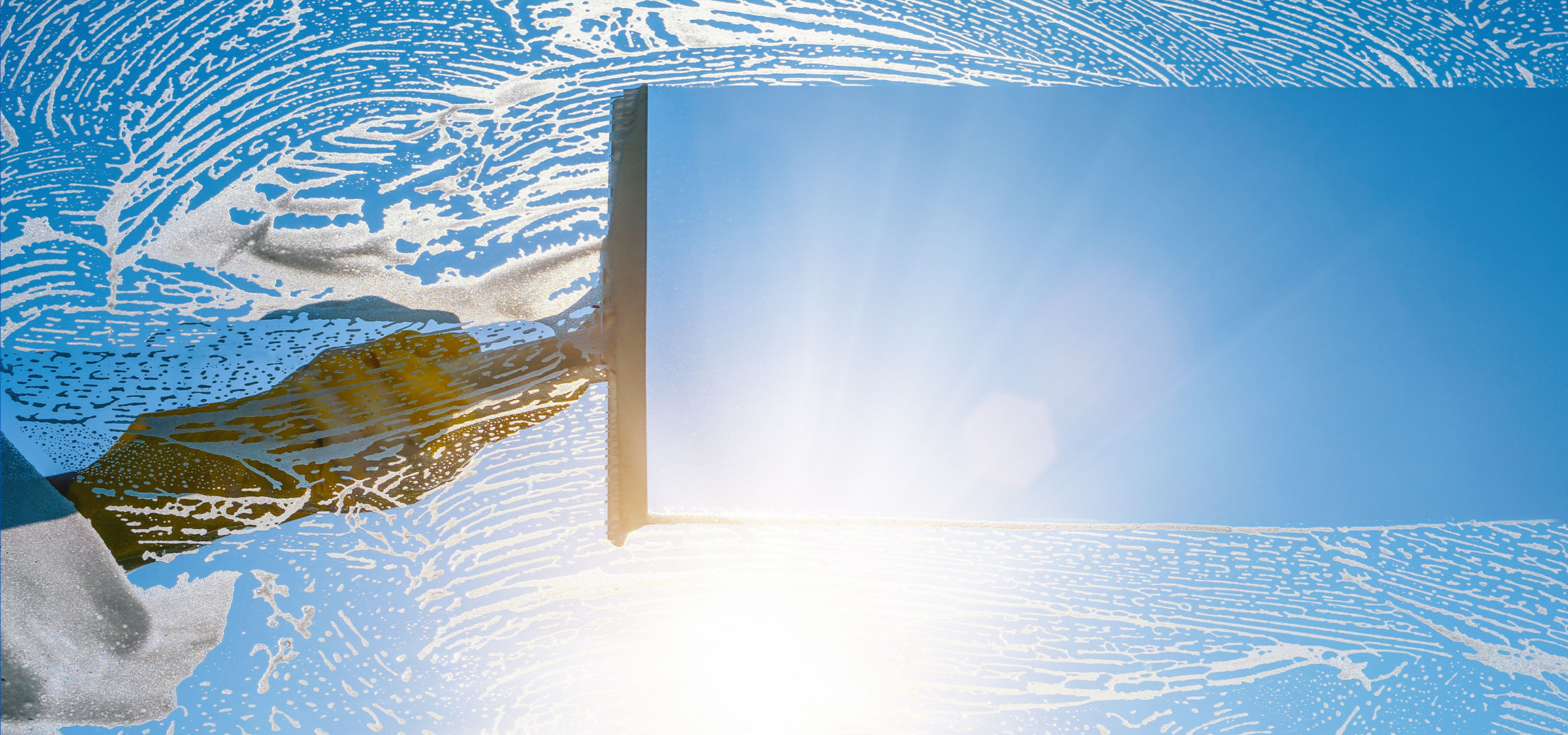 Почистване на прозорци със сапунена пяна на синьо небе.