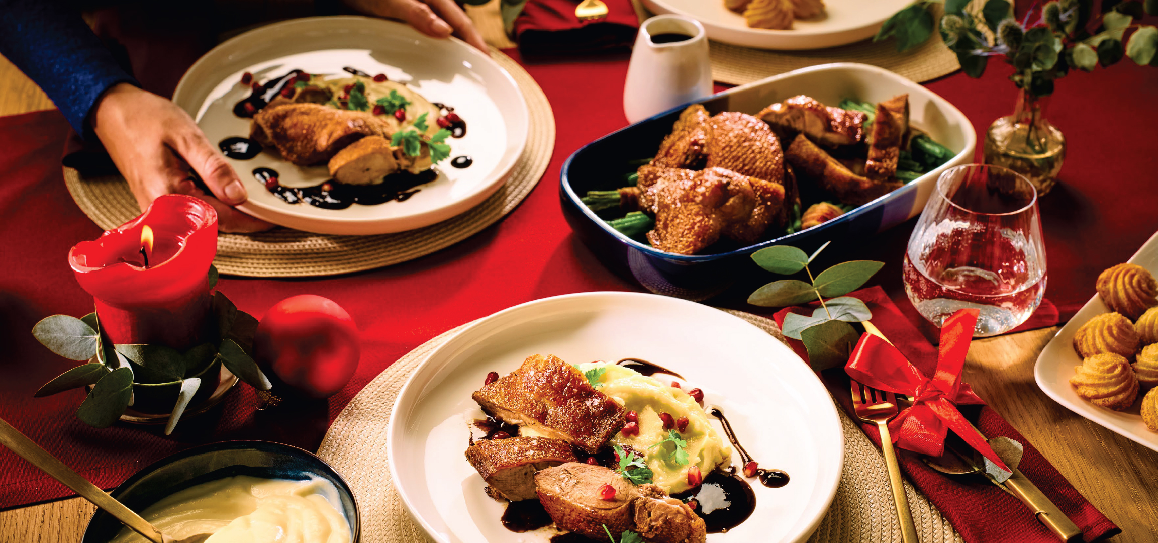 Празнична трапеза с печено месо, гарнитура и червена свещ.