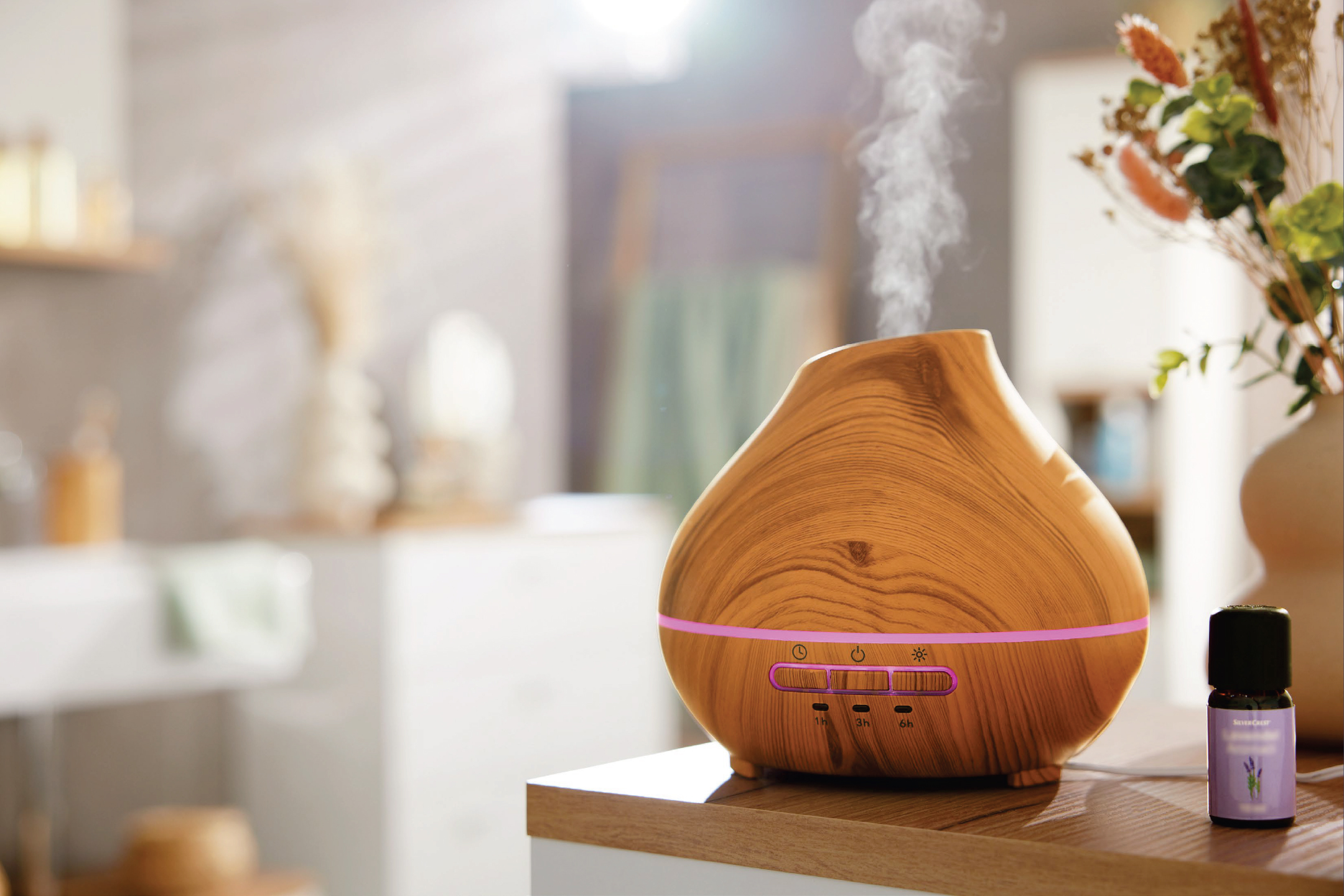 Дървен дифузер за етерични масла с пара и бутилка лавандулово масло на плот.