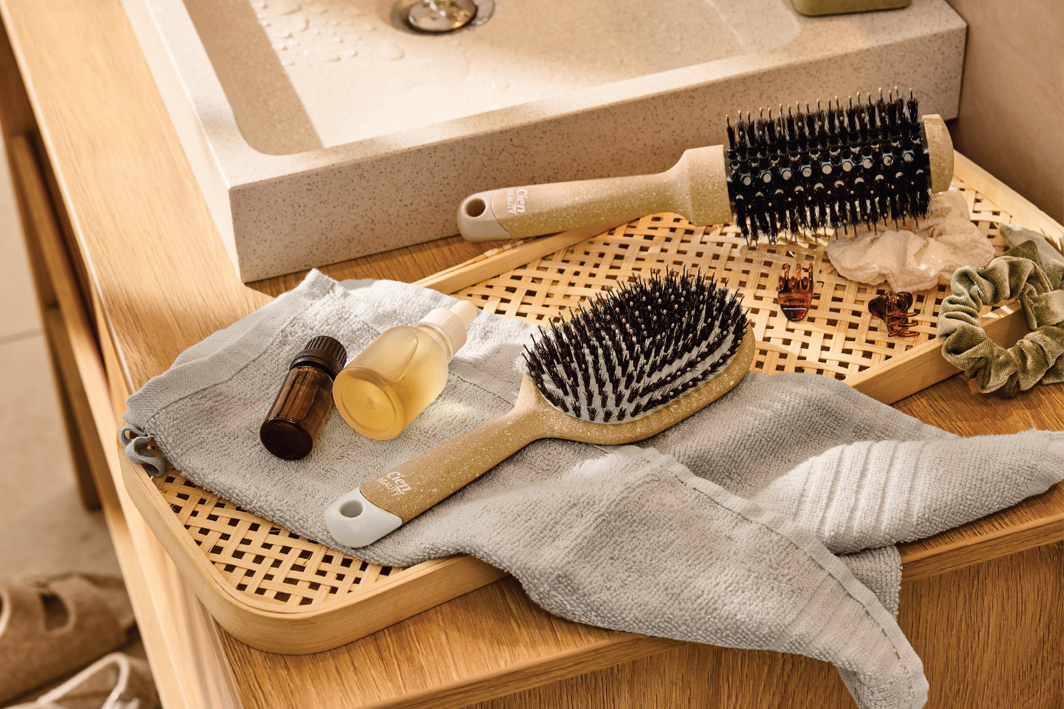 Четки за коса, олио и аксесоари за коса върху дървена табла до мивка.