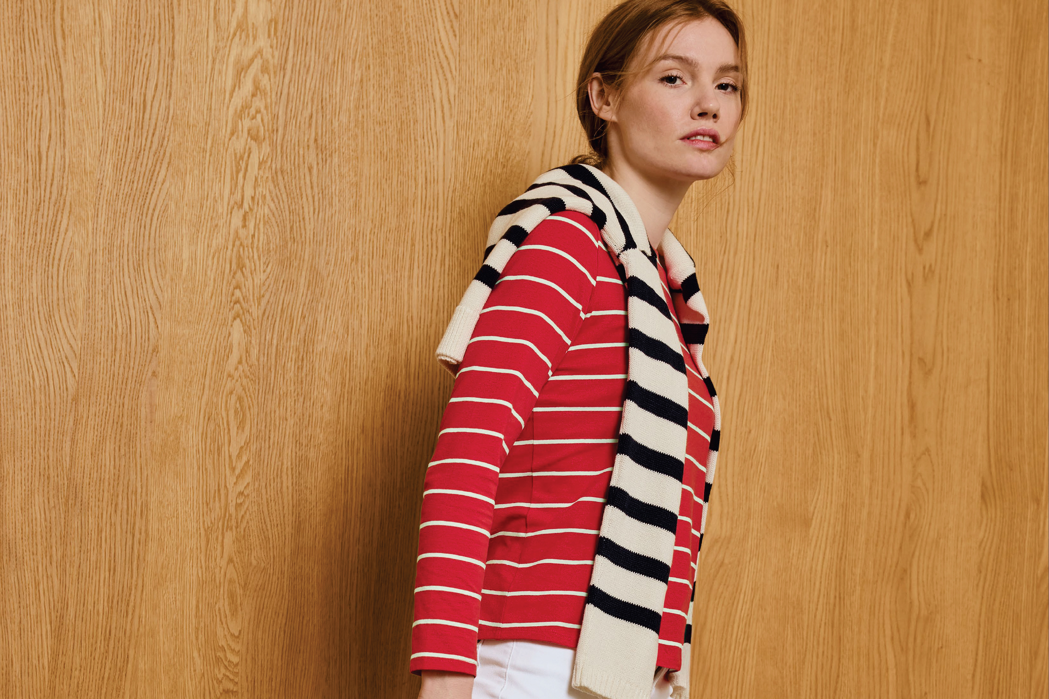 Жена в червена раирана блуза и шал, преметнат през рамо, на дървен фон.