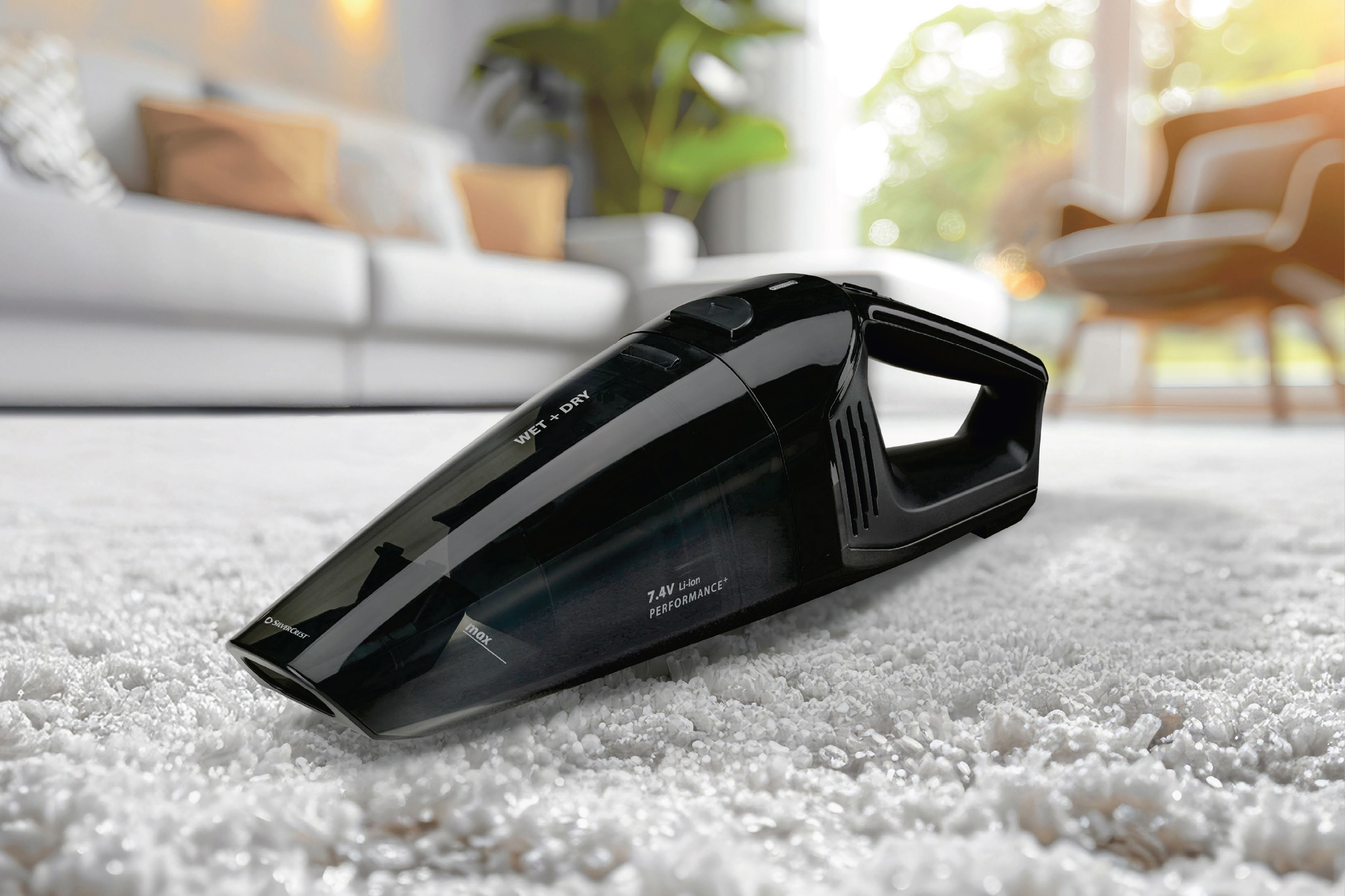 Черна ръчна прахосмукачка за мокро и сухо почистване на бял килим в хол.