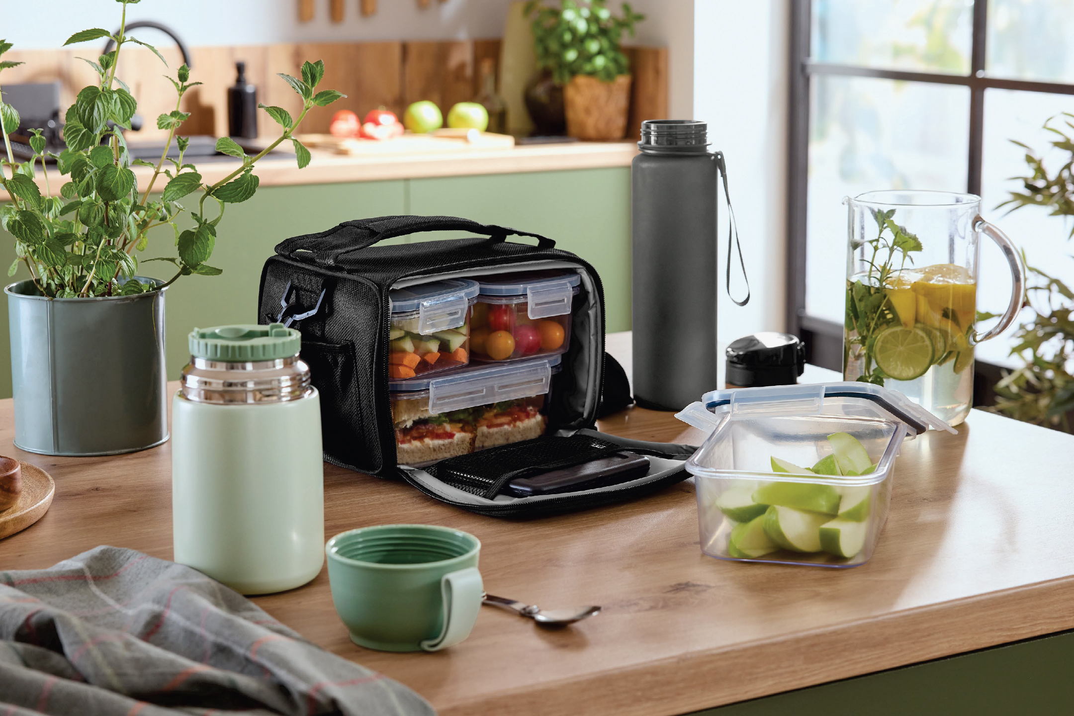 Чанта за обяд с контейнери за храна, термос и бутилка за вода на кухненски плот.