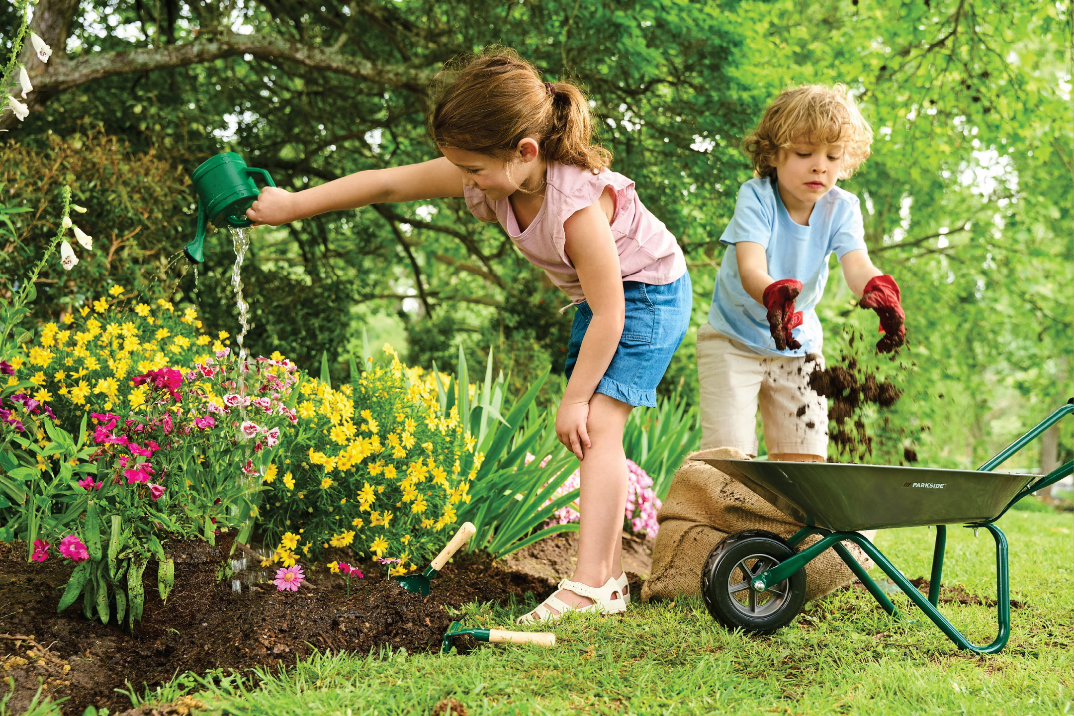 Две деца поливат и засаждат цветя в градината с градински инструменти и количка.