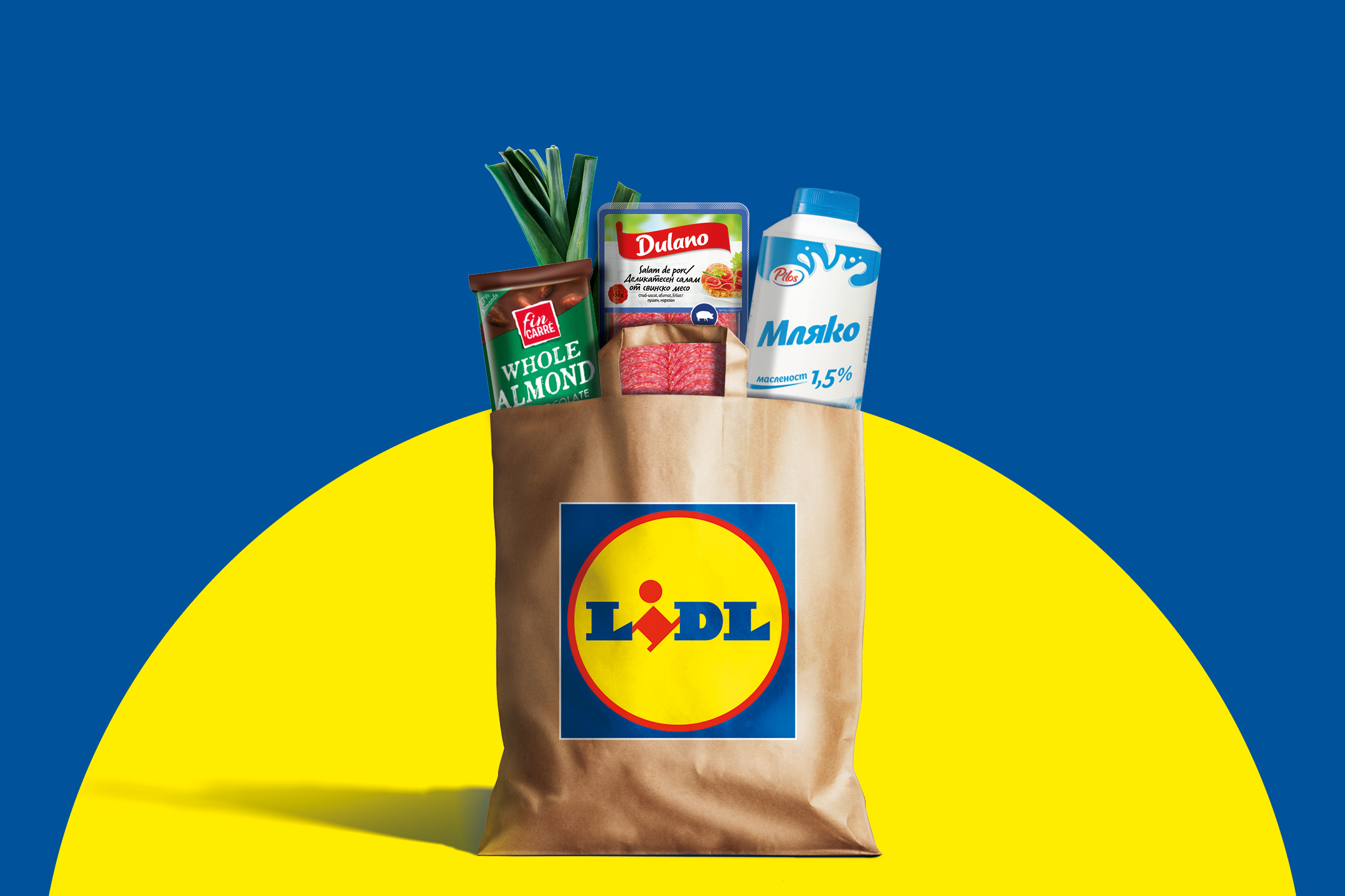 Хартиена торба с хранителни стоки, включително мляко, салам, шоколад и праз, на син и жълт фон.