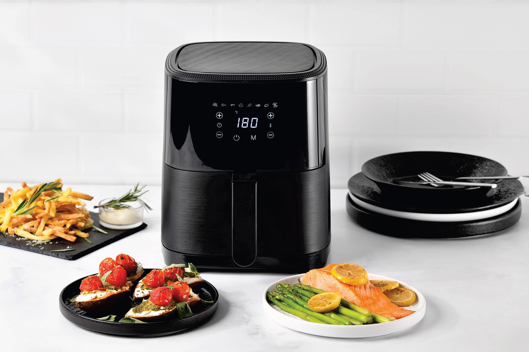 Черен фритюрник с горещ въздух, пържени картофи, брускети и сьомга с аспержи.