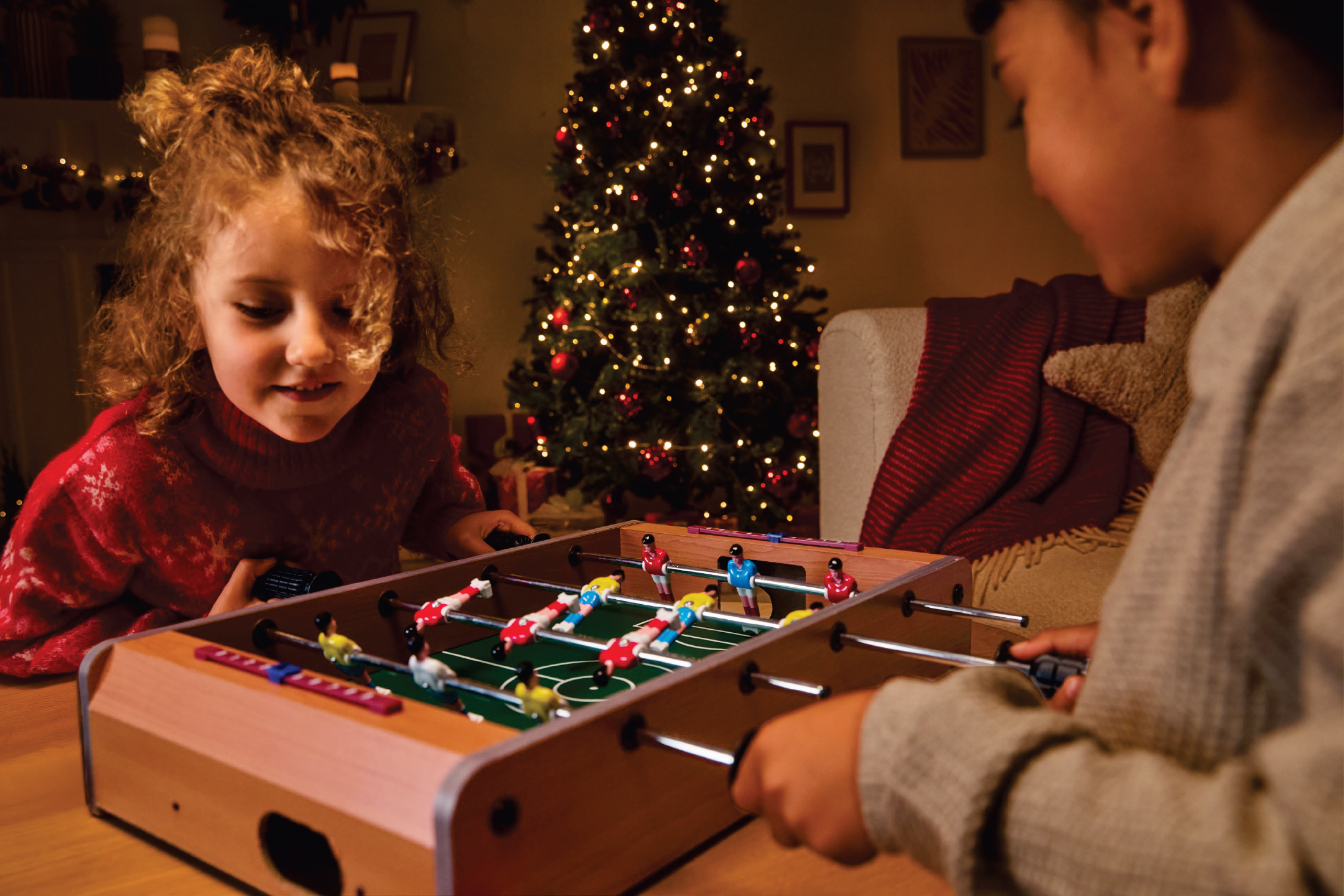 Две деца играят на мини джага пред коледна елха.