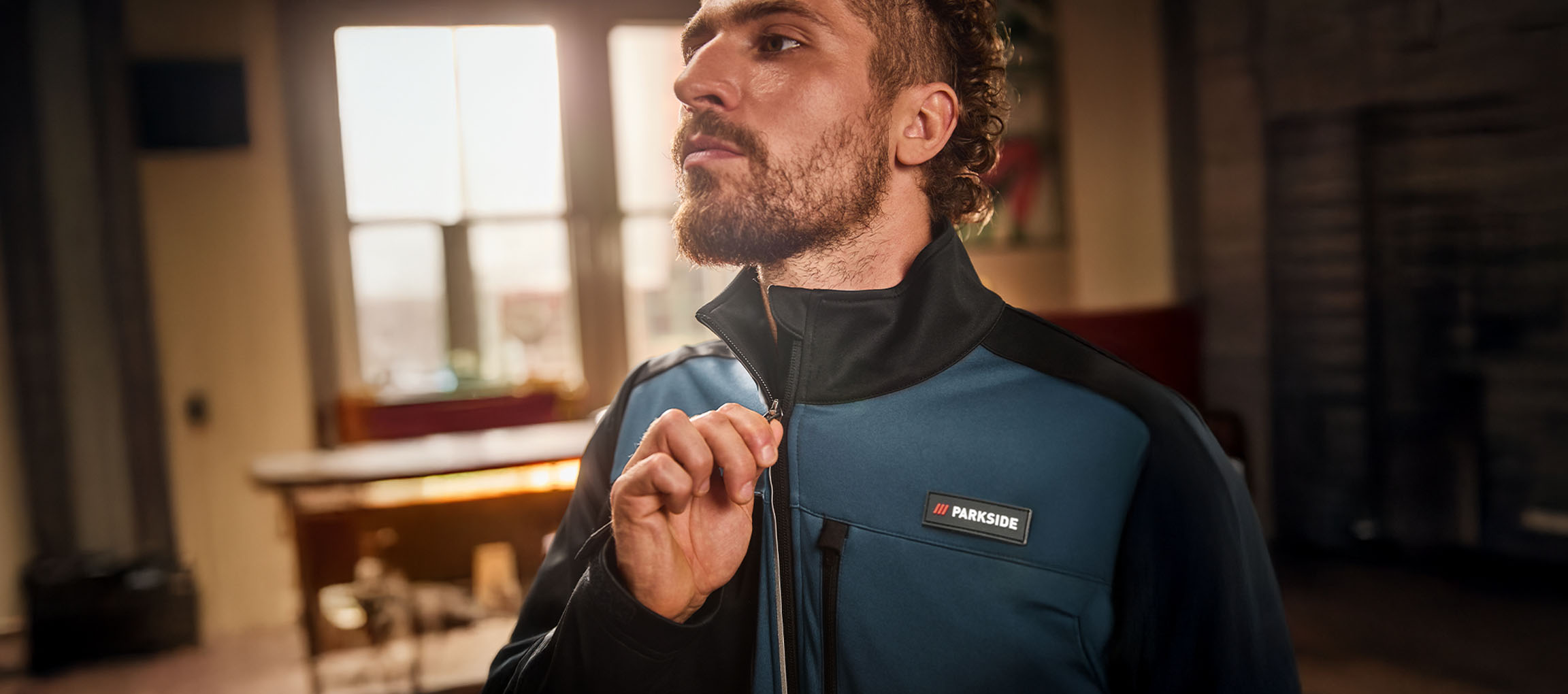 Мъж в синьо-черно работно яке Parkside го закопчава