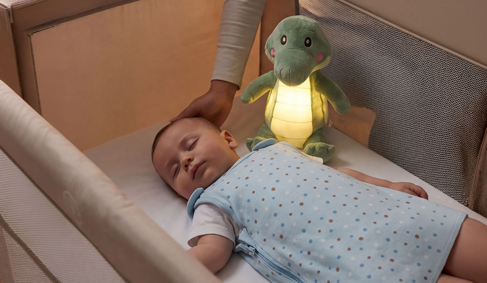 Бебе спи в креватче с плюшена играчка и ръка на родител.