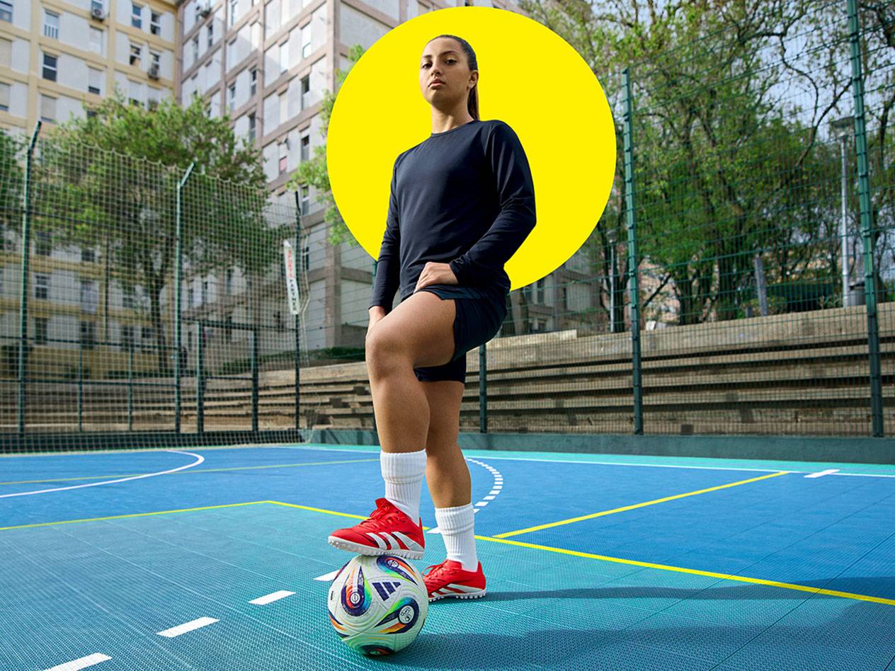 Футболистка с Adidas обувки на синьо игрище.